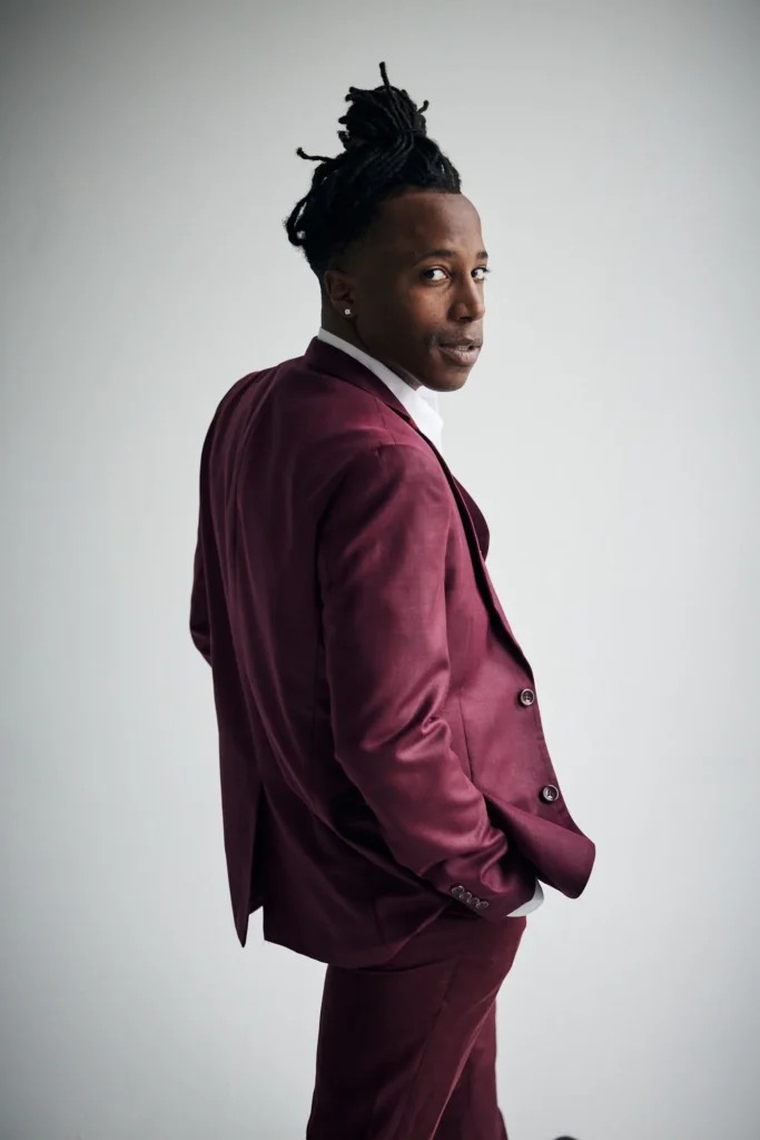Chad Chambers in a burgundy suit glancing over his shoulder in a studio portrait