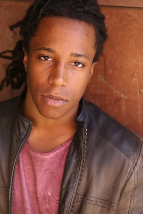 Chad Chambers in a leather jacket against a textured rust-colored wall