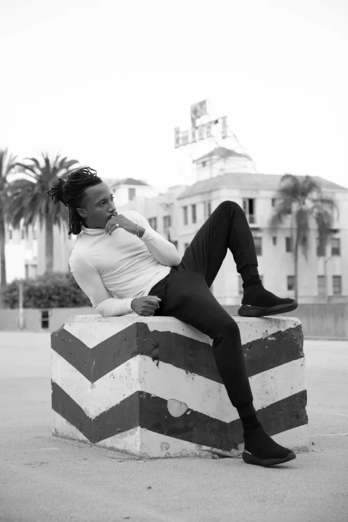 Black-and-white portrait of Chad Chambers reclining on a striped concrete block outdoors